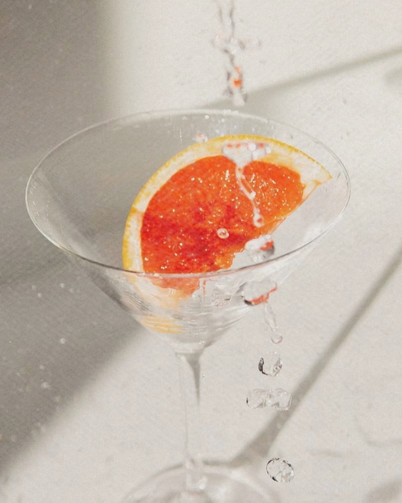 A slice of pink grapefruit in a coupe glass, catching the light