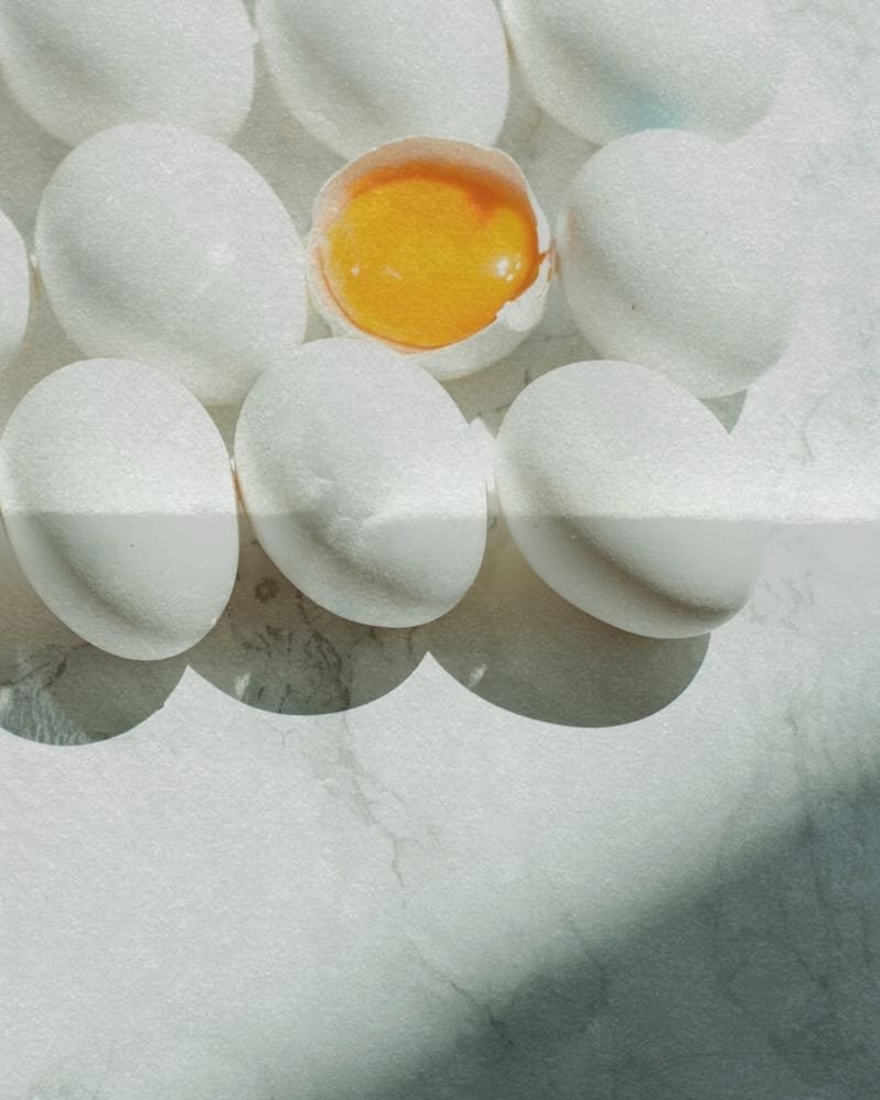 White eggs on a marble surface, one opened to show the yolk