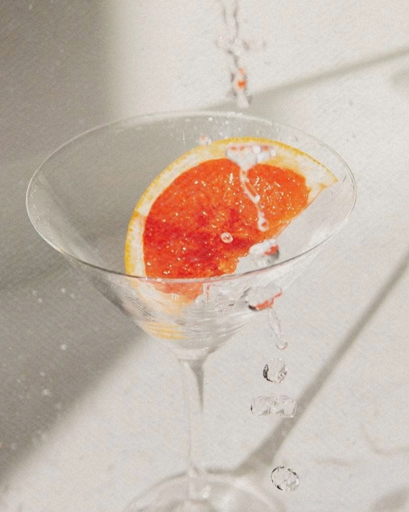 A slice of pink grapefruit in a coupe glass, catching the light